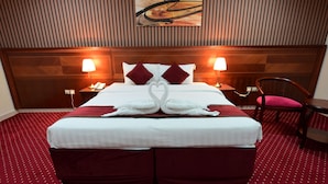 A hotel room with a large bed, two bedside lamps, a wooden headboard, a red carpet, and a wall art piece. - Wefaq Al-Mashaer Hotel (Makkah)