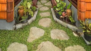 A pathway leading to a building with two wooden archways and a stone staircase. - Sayong Wooden House (Ubud)