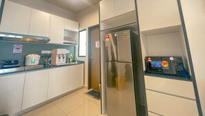 A modern kitchen with white cabinets, a stainless steel refrigerator, a built-in oven, and a coffee machine.