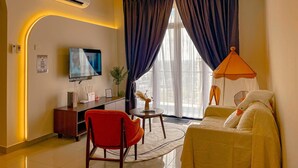 A hotel room with a flat-screen TV, a ceiling fan, a desk with a chair, a sofa, and a large window with curtains.