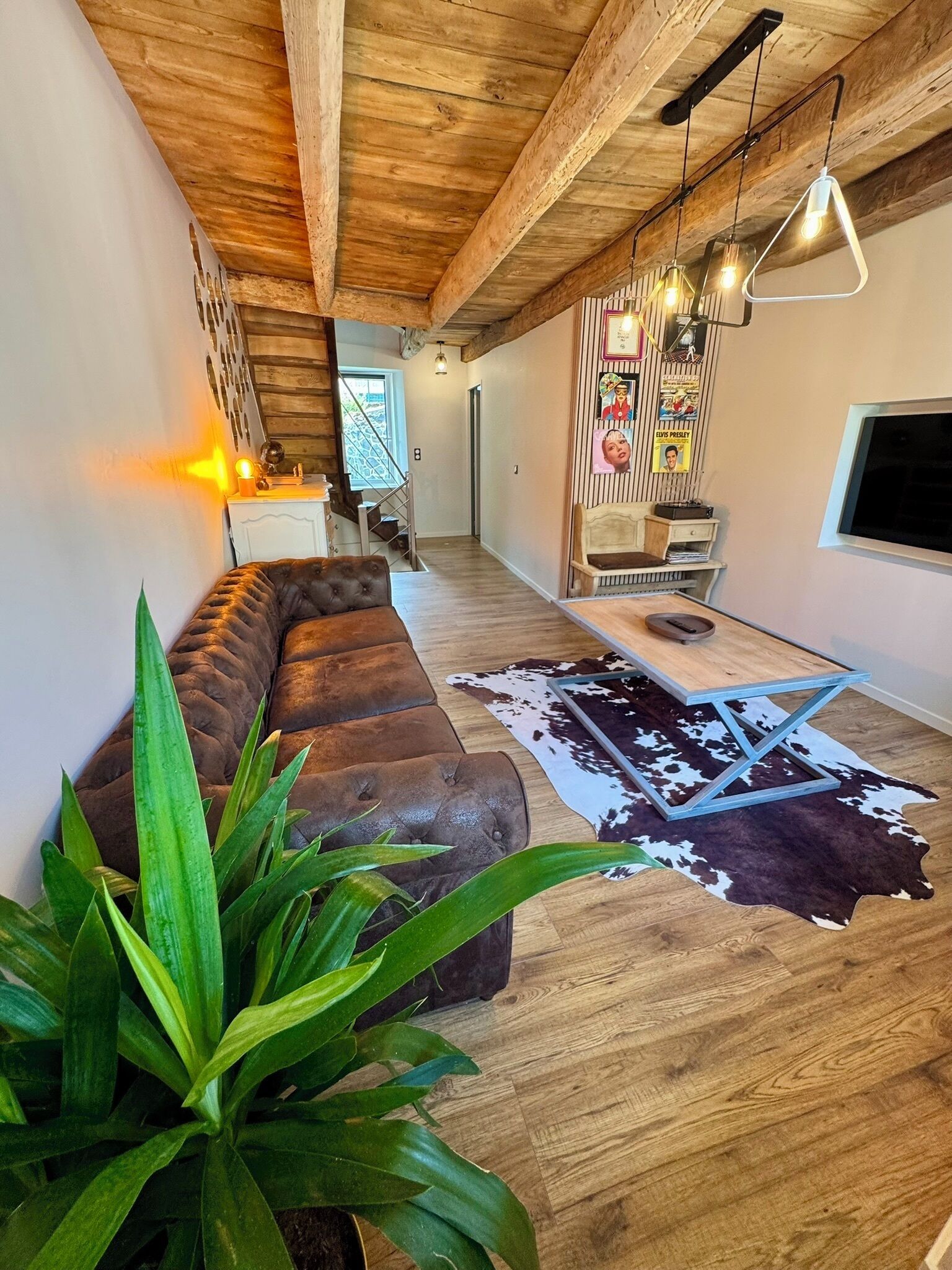 A modern living room with a leather sofa, wooden flooring, and a cowhide rug.