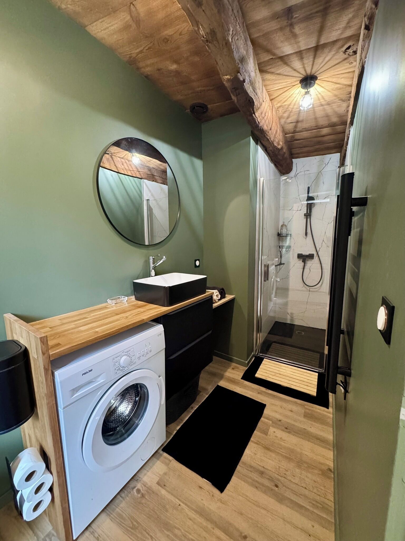 Un baño pequeño con lavadora, lavamanos y ducha.