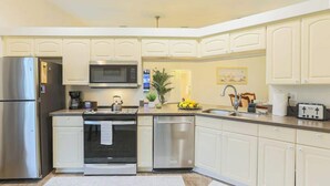 Una cocina moderna con armarios blancos, electrodomésticos de acero inoxidable y una isla central.