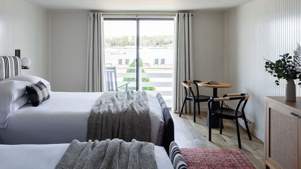 A hotel room with a large bed, a desk, and a view of the outside. - Stylish Coastal Room Perfectly Positioned for Scenic Maine Getaways with Pool (Boothbay)