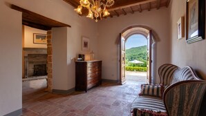 A room with a fireplace, a wooden dresser, a sofa, and an arched doorway leading to a garden. - Villa Fiorda by MMega (Città di Castello)