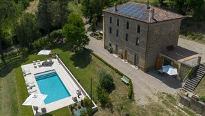 A stone building with a swimming pool, outdoor seating, and a staircase. - Villa Fiorda by MMega (Città di Castello)