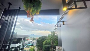 A balcony with a view of a cityscape, a hanging plant, and a sign warning against leaning on the glass. - Room-a304 - 1 Bedroom Condo With Sea Vie (Krabi)