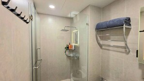 Et moderne badeværelse med en glasbrusekabine, et håndklædetørrestativ og en hylde med toiletartikler.
