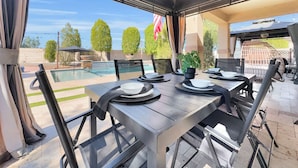 An outdoor patio with a pool, dining setup, and a view of the ocean. - 4BR w pool, fire pit, game room (Queen Creek)