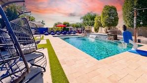 A swimming pool with a clear blue water feature, surrounded by lounge chairs and a red umbrella. - 4BR w pool, fire pit, game room (Queen Creek)