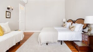 Un dormitorio con dos camas, techo blanco, suelo de madera y alfombra blanca.