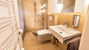 A modern bathroom with a shower, toilet, and sink.