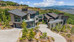 Una casa moderna de varios pisos con fachada de piedra, ventanas grandes y entrada con jardín.
