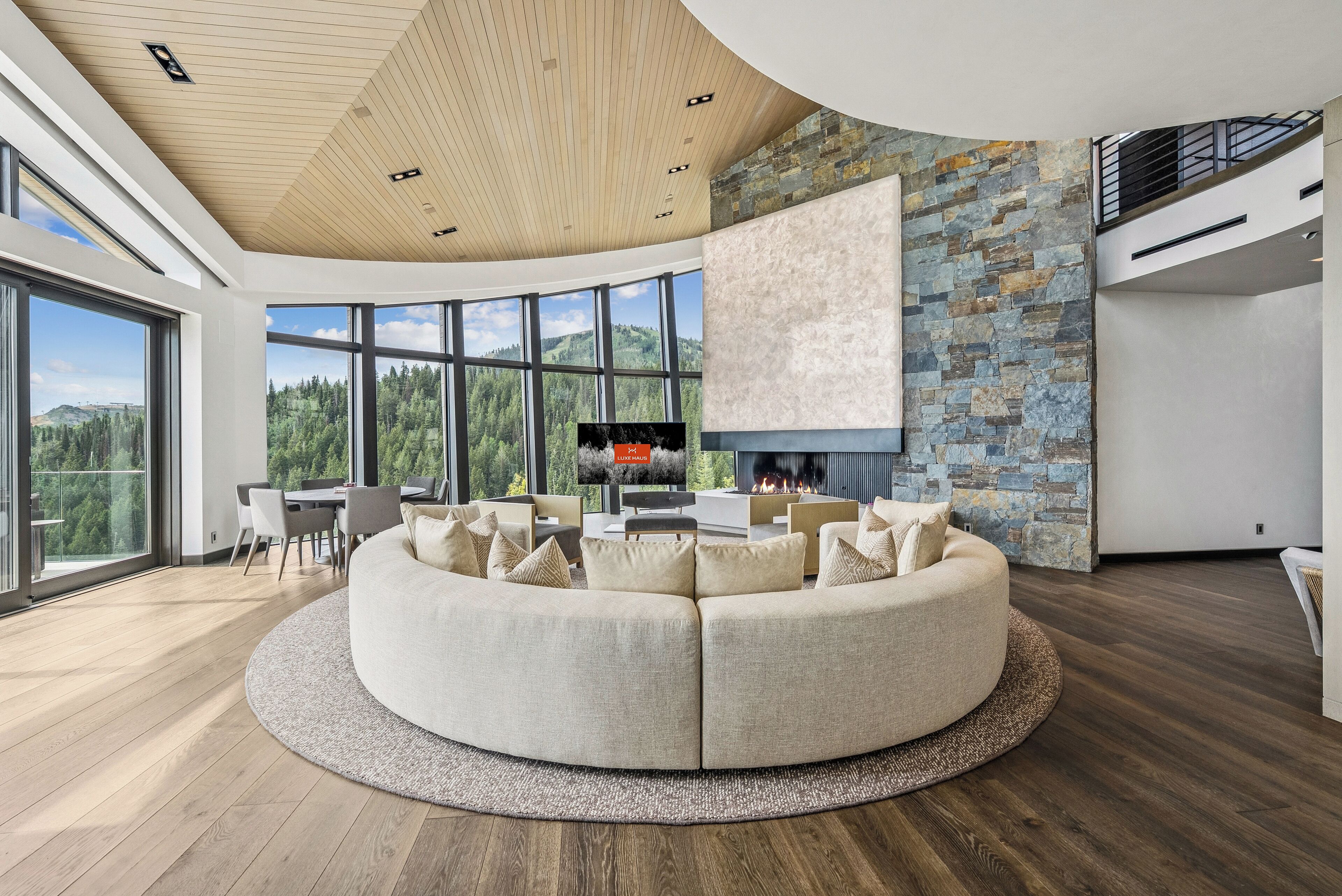 A modern living room with a large sectional sofa, a stone accent wall, and a fireplace.