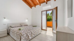 A bedroom with a bed, a nightstand, a wardrobe, and a sliding glass door to a balcony. - Apartment 'Maria Rosa' with Private Terrace, Wi-Fi and Air Conditioning (Teulada)