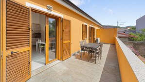 A modern outdoor patio with a dining table and chairs, a sliding glass door entrance, and a view of the surrounding area. - Apartment 'Maria Rosa' with Private Terrace, Wi-Fi and Air Conditioning (Teulada)