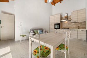 Uma cozinha moderna com armários brancos, forno embutido e coifa de aço inoxidável.