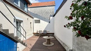 A courtyard with a wooden table and chairs, a blue door, and a white wall with a window. - 🏡 Chez Tata - Authentic vacation home in the heart of Le Crotoy (Le Crotoy)