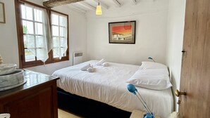 A bedroom with a bed, a desk with a bowl, a painting on the wall, and a window with curtains. - 🏡 Chez Tata - Authentic vacation home in the heart of Le Crotoy (Le Crotoy)