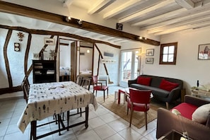 A room with a dining table, chairs, a sofa, and a fireplace.