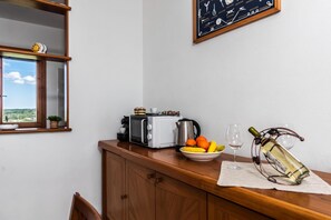 A kitchen with a toaster, kettle, and a bowl of fruit on the counter. - La Guzzetta Stintinese (Stintino)