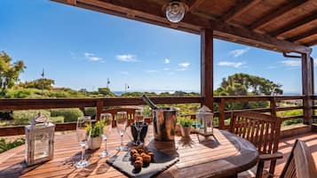 A wooden deck with a table set for a meal, overlooking a scenic landscape.