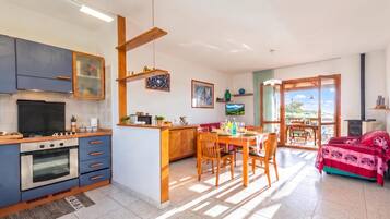 A modern kitchen with a dining area, featuring a stove, oven, and wooden cabinets.