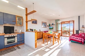 A modern kitchen with a dining area, featuring a stove, oven, and wooden cabinets. - La Guzzetta Stintinese (Stintino)