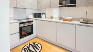 Una cocina moderna con armarios grises, horno empotrado, microondas, tostadora y lavabo.