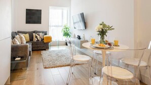 Una sala moderna con sofá, mesa de centro y comedor con sillas.