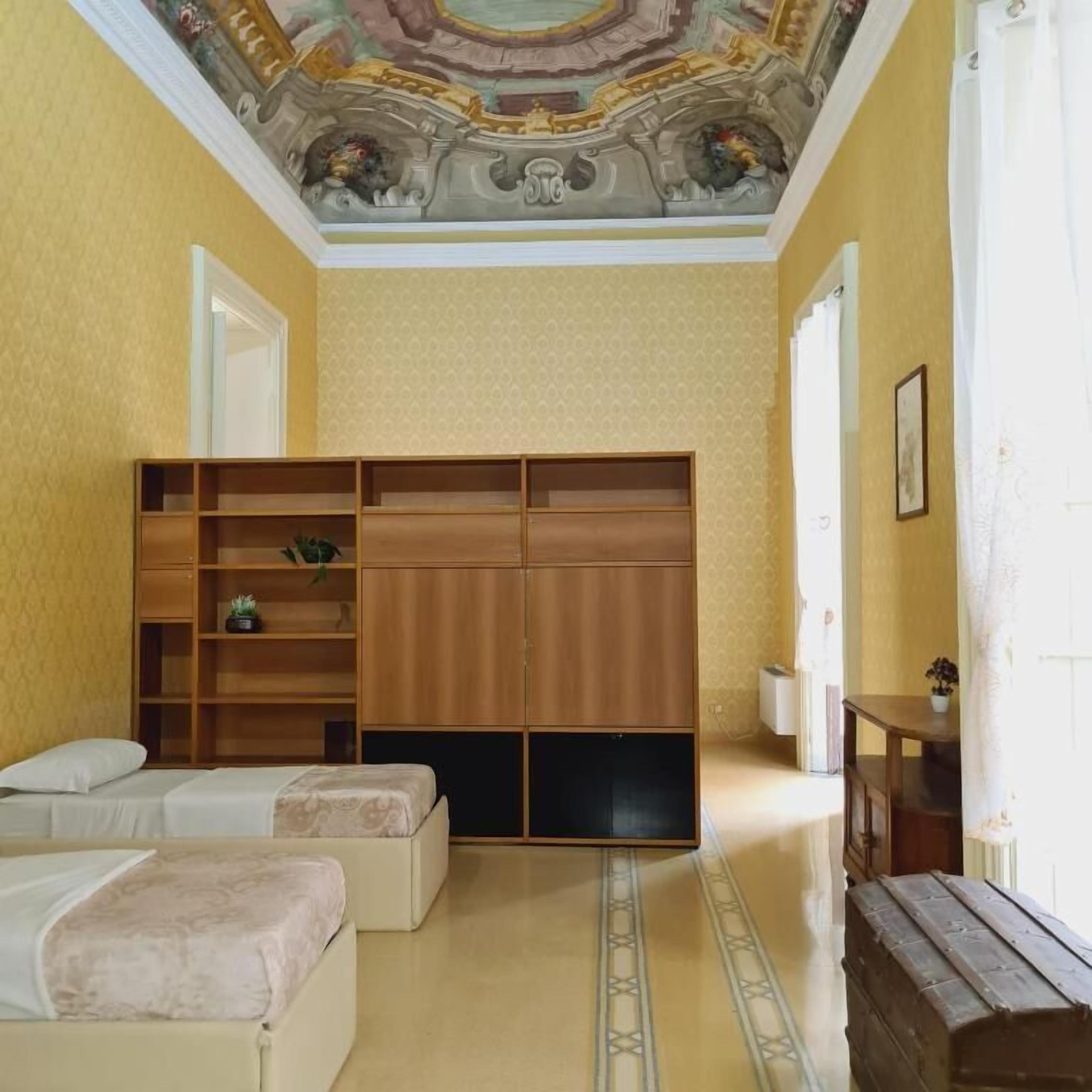 A room with a bed, a wardrobe, and a small table with a plant.