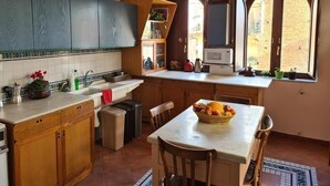 Een keuken met houten kastjes, een wit aanrecht, een spoelbak, een magnetron en een raam met uitzicht op de straat.