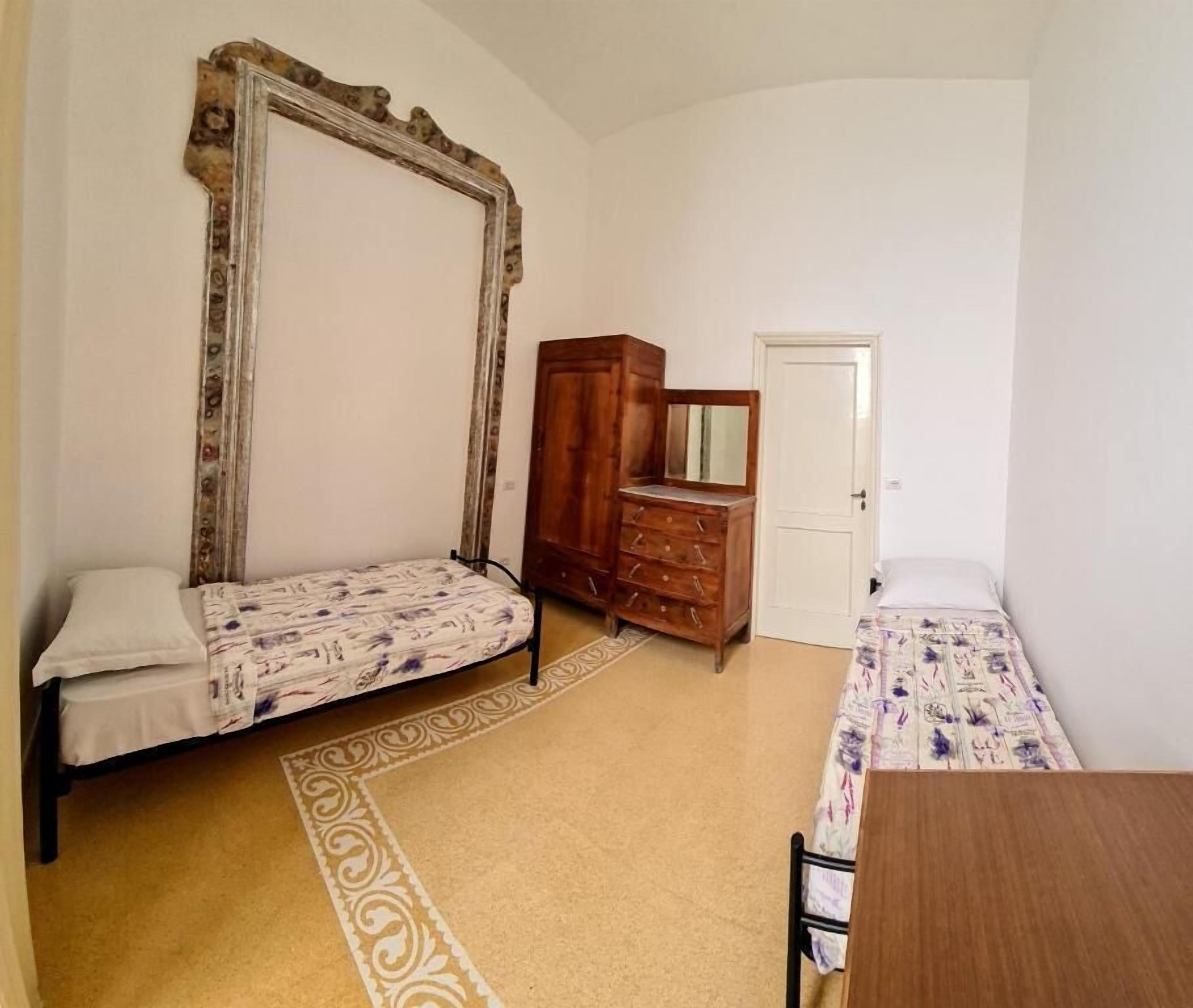 Un dormitorio con dos camas individuales, un armario de madera, un espejo y una puerta.