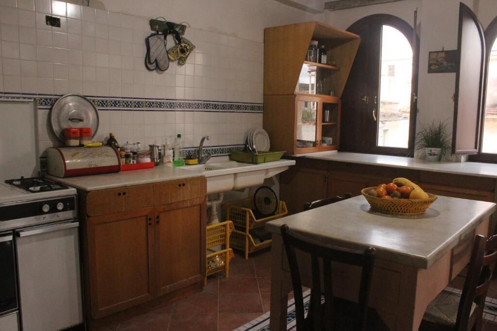 A kitchen with a stove, sink, wooden cabinets, and a dining area with a table and chairs.