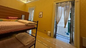 A room with two beds, a balcony with a railing, and a decorative ceiling. - Salerno Experience HOSTEL (Salerno)