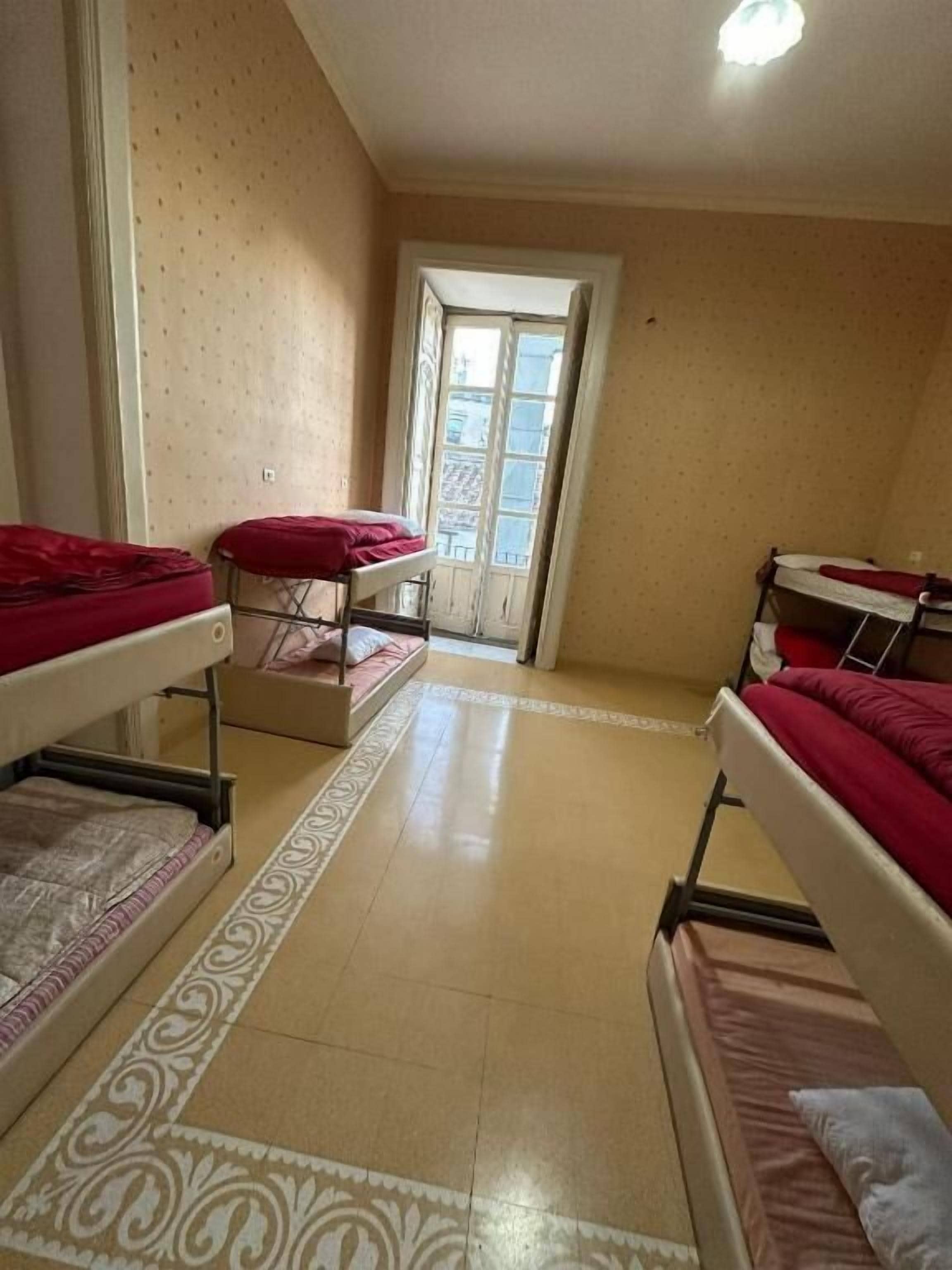 Un dormitorio con literas, una alfombra estampada y una ventana con cortinas.