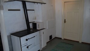 A compact kitchen with a stove, oven, and microwave. There is a door and a small window. - Malaskog nature reserve Baden (Malaskog)