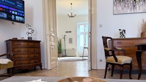 Una sala de estar con un aparador de madera, una silla, un televisor mostrando la interfaz de Disney+ y un cuenco con objetos de madera sobre una mesa.