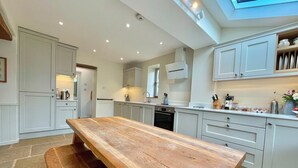 Una cocina moderna con una mesa de comedor de madera, armarios blancos y un tragaluz.