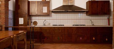 Una cocina con armarios de madera, una estufa a gas y un salpicadero de azulejos.