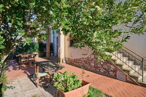 Une terrasse avec des meubles d’extérieur, un escalier et un mur en pierre.