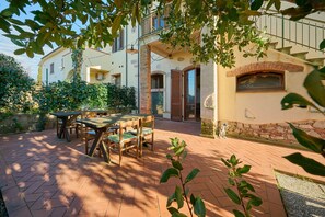 Un patio con una mesa y sillas, un muro de piedra y un edificio con balcón.