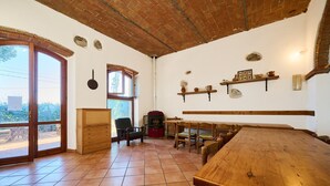 A dining area with a wooden table and chairs, a fireplace, and a large window with a view. - Room 'Contessa Beatrice' with Shared Garden and Wi-Fi (San Vincenzo)