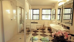 Een badkamer met een glazen douchecabine, een badkuip, een toilet en een wastafel met een spiegel.