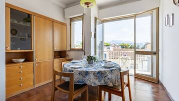 Un comedor con una mesa redonda, sillas, un mueble de madera y vistas a través de un ventanal.