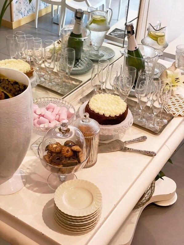 Una mesa dispuesta con copas de cristal, una botella de champán y diversos postres.