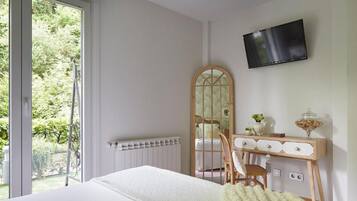 Een slaapkamer met een bed, een dressoir, een spiegel en een televisie.
