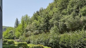 A well-maintained garden with a round table and chairs, surrounded by neatly trimmed hedges and a variety of plants. - Txanka Erreka (Orio)