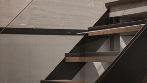Un escalier moderne avec des marches en bois et des rampes en métal noir.