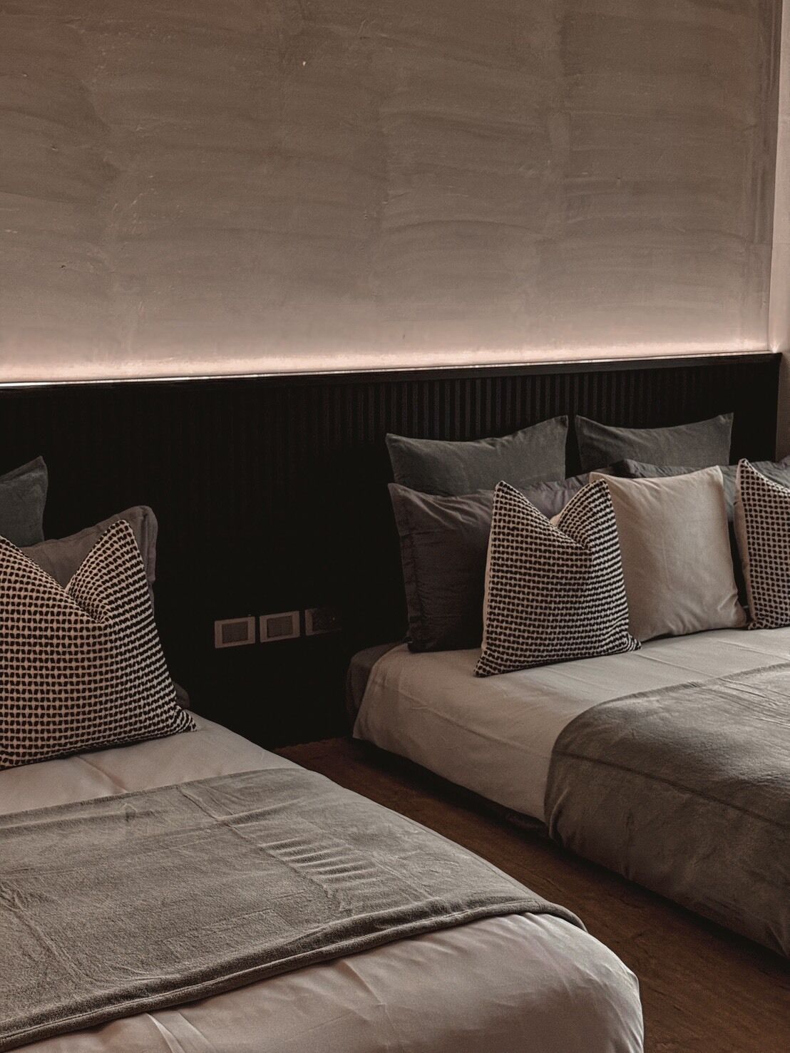 A hotel room with two beds, each with a headboard, and a large window above.